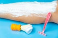 Procedure for preparing legs for hair removal with a pink disposable razor on a blue background, next to it is an orange shaving