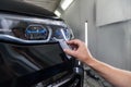 The process of applying a nano-ceramic coating on the car`s bumper by a male worker with a sponge and special chemical compositio