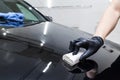 The process of applying a nano-ceramic coating on the car`s hood by a male worker with a sponge and special chemical composition