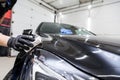 The process of applying a nano-ceramic coating on the car`s hood by a male worker with a sponge and special chemical composition