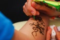 The process of applying to the skin ornament painted with henna. Royalty Free Stock Photo