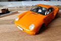 The process of assembling and painting the scale model of the car. Orange sports car in miniature. Installed front headlights