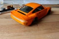 The process of assembling and painting the scale model of the car. Orange sports car in miniature. Installed taillights Royalty Free Stock Photo
