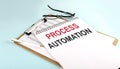 PROCESS AUTOMATION text on notepad on clipboard with chart on blue background, concept closeup. Business and finance concept Royalty Free Stock Photo