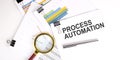 PROCESS AUTOMATION text on white paper on light background with charts paper
