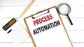 PROCESS AUTOMATION words on clipboard, with calculator, magnifier and pencil on the white wooden background Royalty Free Stock Photo