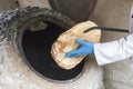 process of baking bread in a traditional Georgian stove - tone, tandoor. A male cook takes a fresh tortilla from the oven Royalty Free Stock Photo