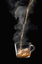 Process brewing tea on black background. Transparent glass cup of freshly brewed black tea steaming isolated