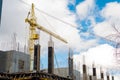 The process of building a multi-storey residential building, a yellow tower crane, poured concrete columns with fittings against a Royalty Free Stock Photo