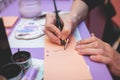 Process of calligraphy handwriting with an ink fountain pen feather, calligrapher practicing writing on a postcard paper using pen