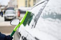 The process of cleaning snow from a car with a brush.