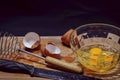 Process of cooking. In a glass bowl, three eggs, next to a knife, whisk for whipping, eggshell