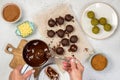 Woman`s hands cover candy with tempered chocolate.