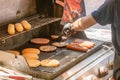 Process of cooking meat for burgers and cheeseburgers, sausages for hot dogs, buns on a grill with burning coals. Royalty Free Stock Photo