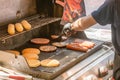 Process of cooking meat for burgers and cheeseburgers, sausages for hot dogs, buns on a grill with burning coals.