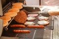 Process of cooking meat for burgers and cheeseburgers, sausages for hot dogs, buns on a grill with burning coals. Royalty Free Stock Photo