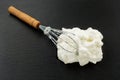 Process of cooking meringue. Whipped egg whites on whisk on slate background. Baking dessert concept