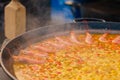 Process of cooking paella with shrimp, musse, rice in huge pan - close up