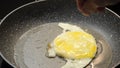 Adding spices to fried eggs in a frying pan