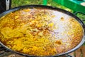 Process of cooking Spanish paella or jambalaya in large flat frying pan. Ingredients meat, rice, vegetables, simmering in broth