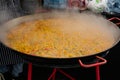 Process of cooking yellow paella in huge paella pan