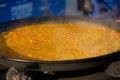 Process of cooking yellow paella with tomato, rice in huge pan - close up