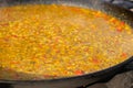 Process of cooking yellow paella with tomato, rice in huge pan - close up