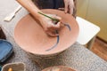 Potter woman paints a ceramic plate closeup. Girl draws with a brush on earthenware. Process of creating clay products. Royalty Free Stock Photo