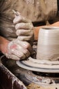 The process of creating a pottery on a twisted Potter`s wheel close-up. Dirty hands in the clay and the potter`s wheel Royalty Free Stock Photo