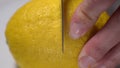 The process of cutting a ripe yellow lemon into two parts with a knife