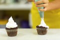 The process of decorating chocolate cupcakes with airy protein cream. Creation of cakes by professional pastry chefs Royalty Free Stock Photo