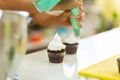 The process of decorating chocolate cupcakes with airy protein cream. Creation of cakes by professional pastry chefs Royalty Free Stock Photo