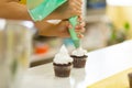 The process of decorating chocolate cupcakes with airy protein cream. Creation of cakes by professional pastry chefs Royalty Free Stock Photo