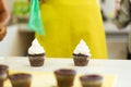 The process of decorating chocolate cupcakes with airy protein cream. Creation of cakes by professional pastry chefs Royalty Free Stock Photo