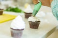 The process of decorating chocolate cupcakes with airy protein cream. Creation of cakes by professional pastry chefs