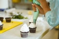 The process of decorating chocolate cupcakes with airy protein cream. Creation of cakes by professional pastry chefs Royalty Free Stock Photo
