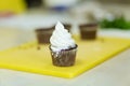 The process of decorating chocolate cupcakes with airy protein cream. Creation of cakes by professional pastry chefs Royalty Free Stock Photo