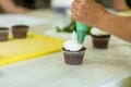 The process of decorating chocolate cupcakes with airy protein cream. Creation of cakes by professional pastry chefs Royalty Free Stock Photo