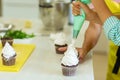 The process of decorating chocolate cupcakes with airy protein cream. Creation of cakes by professional pastry chefs Royalty Free Stock Photo