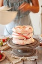 Process of decorating meringue cake with whipped cream and fresh strawberry