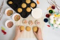 The process of decorating mini cupcakes Easter cakes with white icing and sweet candies, top view, willow branches and eggs for