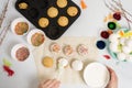 The process of decorating mini cupcakes Easter cakes with white icing and sweet candies, top view, willow branches and eggs for