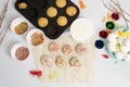 The process of decorating mini cupcakes Easter cakes with white icing and sweet candies, top view, willow branches and eggs for