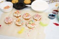 The process of decorating mini cupcakes Easter cakes with white icing and sweet candies, top view, willow branches and eggs for
