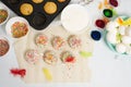 The process of decorating mini cupcakes Easter cakes with white icing and sweet candies, top view, willow branches and eggs for