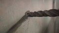 Process of drilling hole in concrete wall using electric drill or perforator. Close up of metal spiral auger drill. In