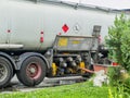 Process of a fuel transfer from a tank truck into filling station gas reservoir. Side view of tank track and connected hose Royalty Free Stock Photo