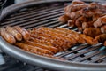 Process of grilling fresh meat sausages on big round hanging grill - close up