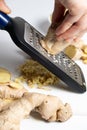 The process of grinding fresh ginger root on a grater Royalty Free Stock Photo