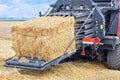 The process of harvesting grain in an agricultural field, forming sheaves of straw into tight briquettes